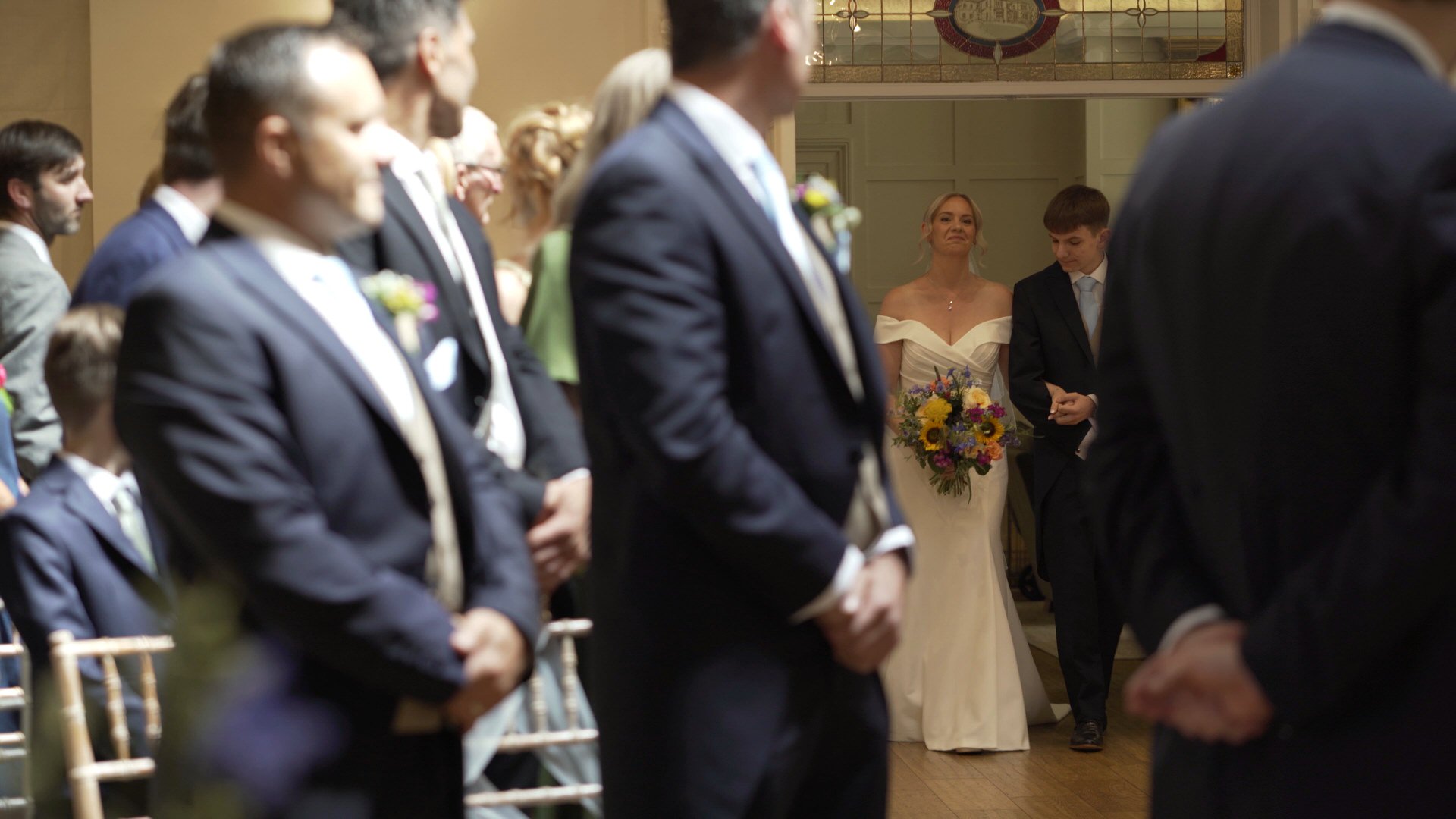a videographer captures the bride walking down the aisle with her son at Ashfield House wedding