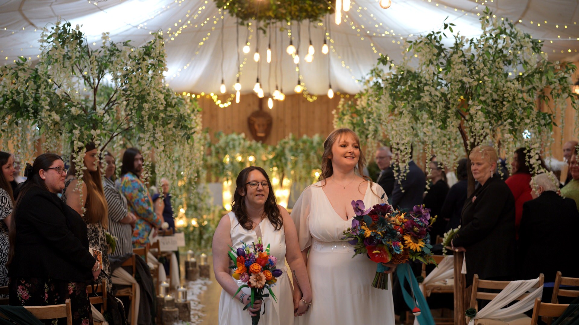 brides walk back down the aisle smiling for the videographer and guests at the wellbeing farm in Bolton Lancashire