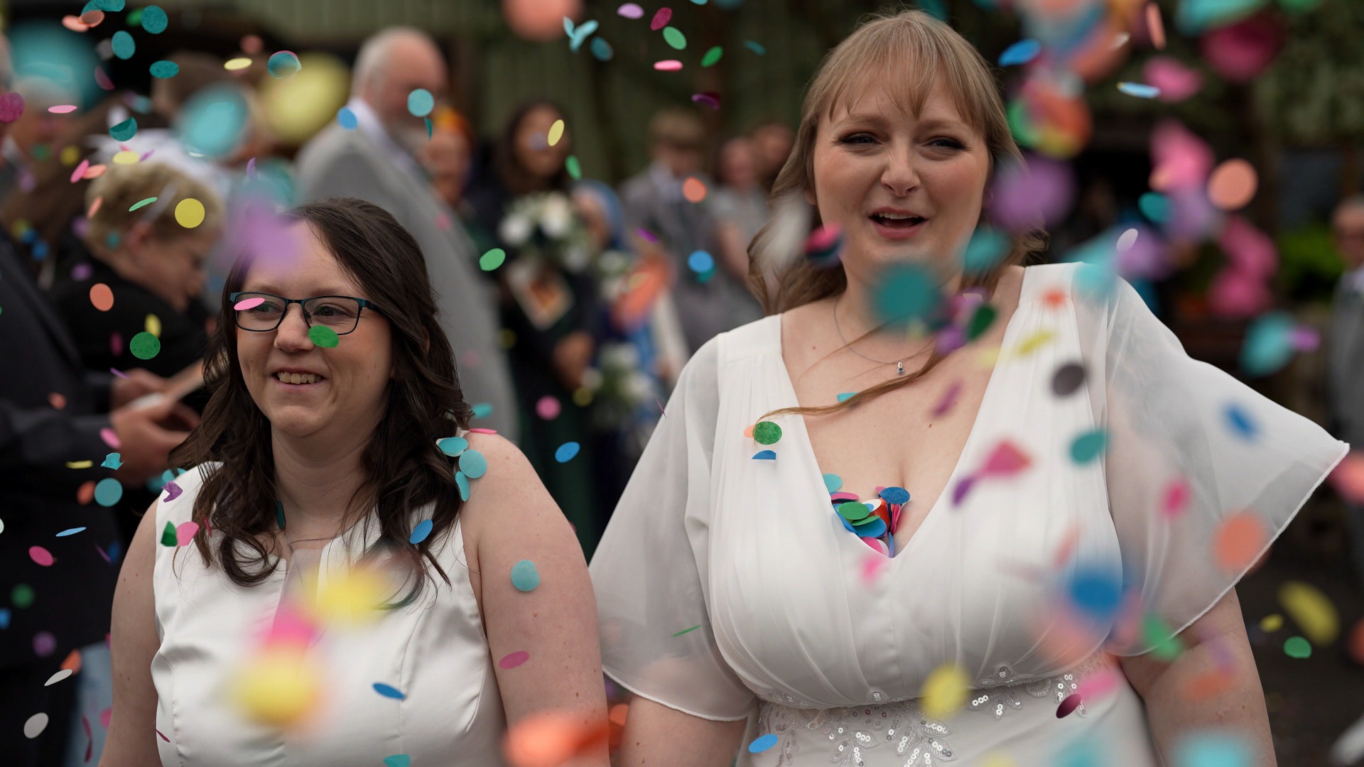 a videographer captures the fun of confetti in the rain outside the wellbeing farm in Bolton Lancashire
