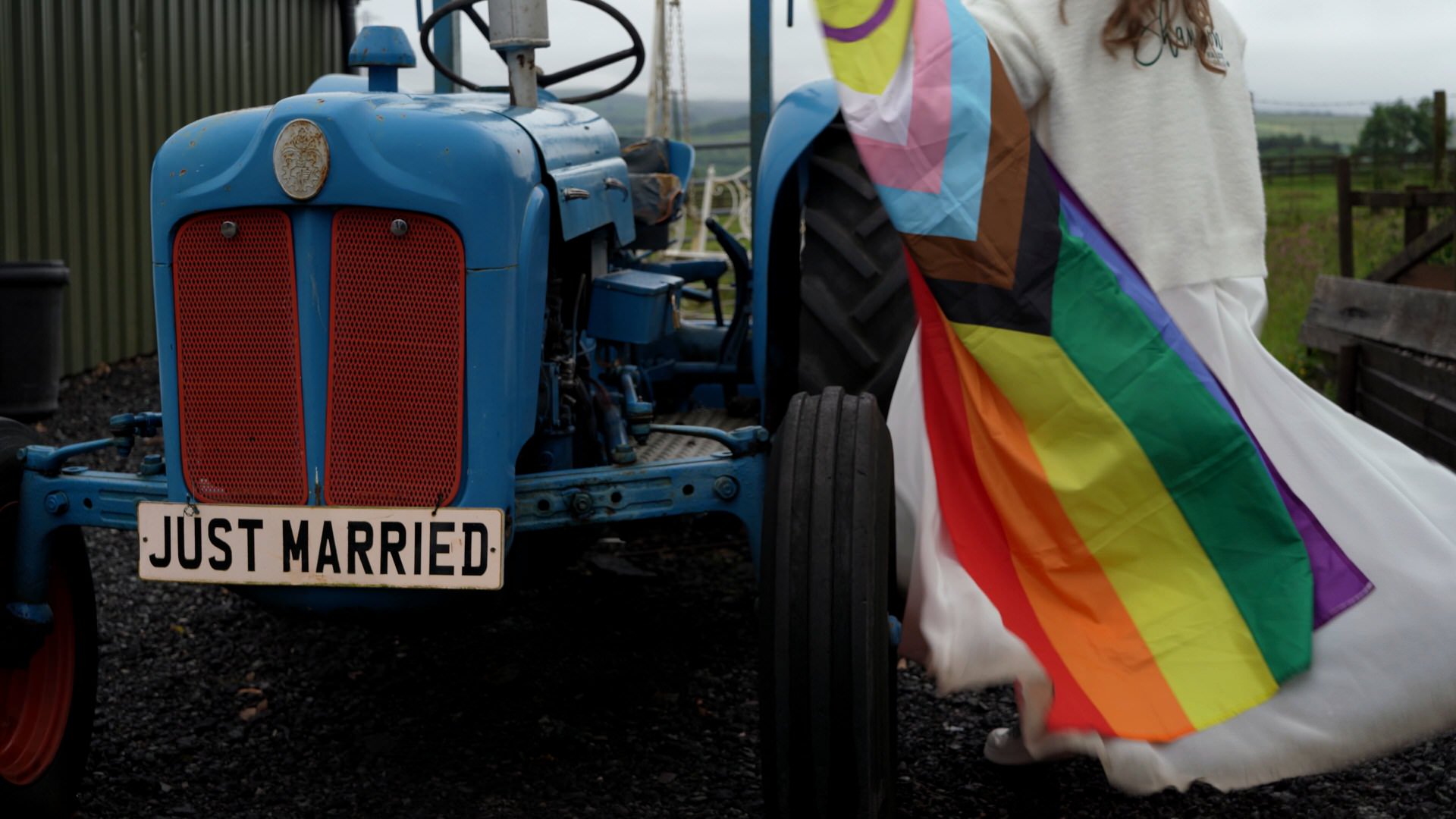 a bride climbs on to a vintage tractor with a pride rainbow flag at the wellbeing farm in Bolton Lancashire