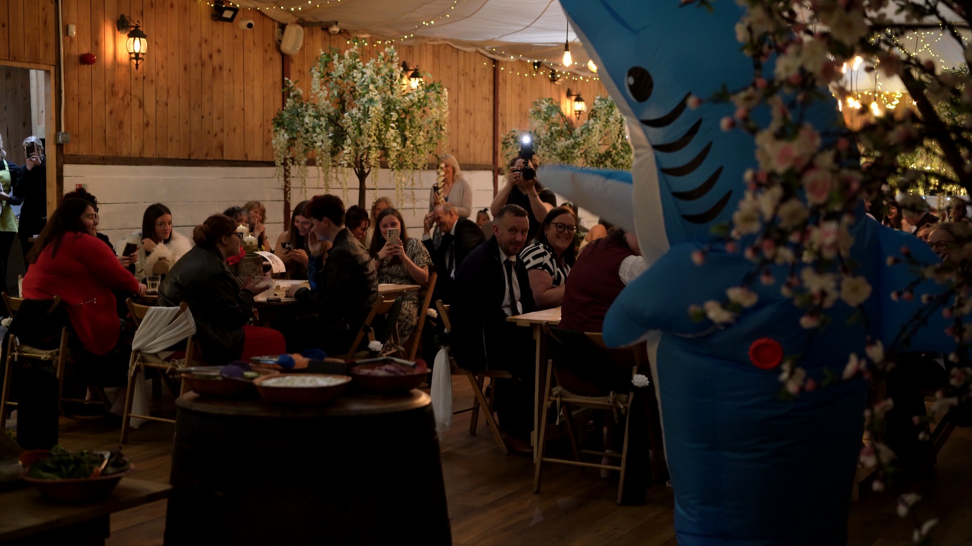 guests clap along to the mother of the bride in an inflatable shark costume