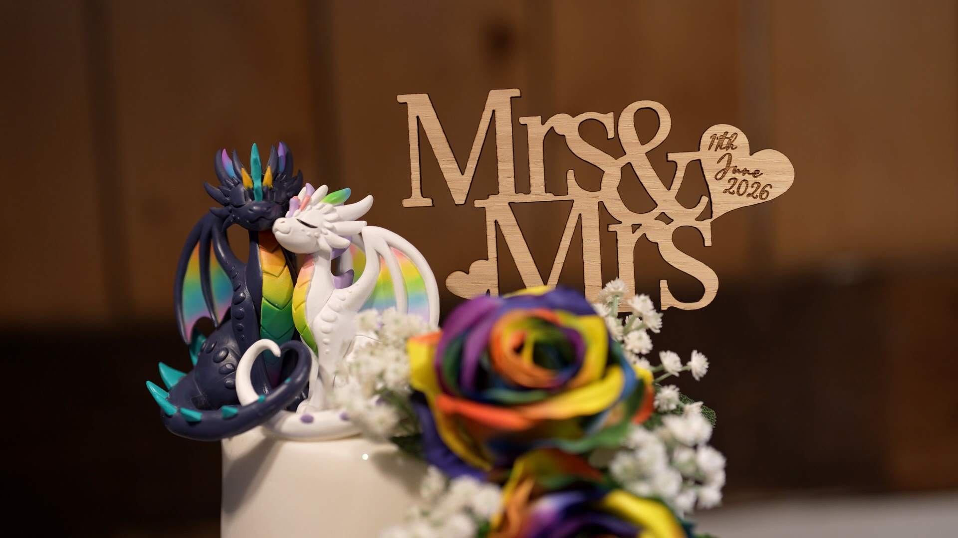 a close up of a rainbow cake with two female dragons cuddling