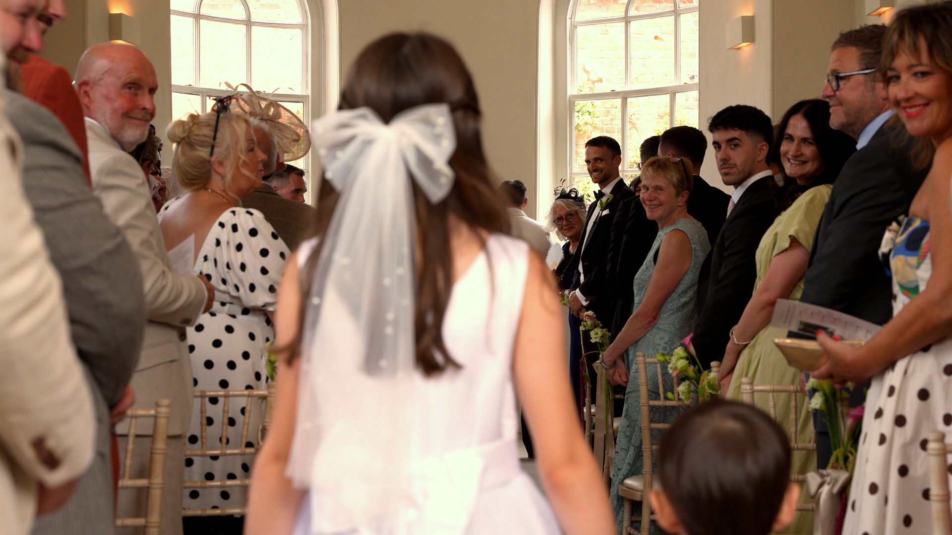 a flowergirl and pageboy walk down the aisle. videographer captures guest reactions at at Iscoyd Park