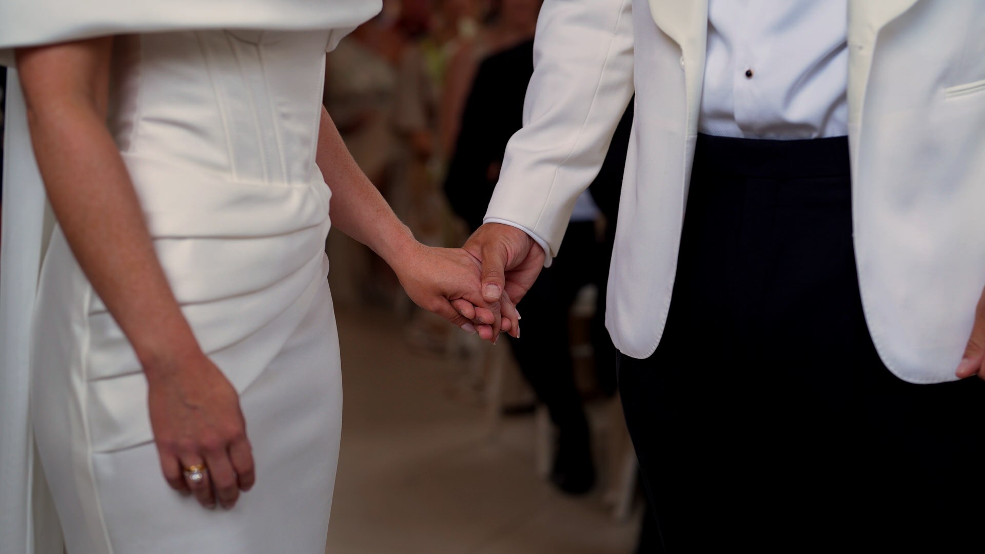 a close up video still of the couple holding hands during the ceremony