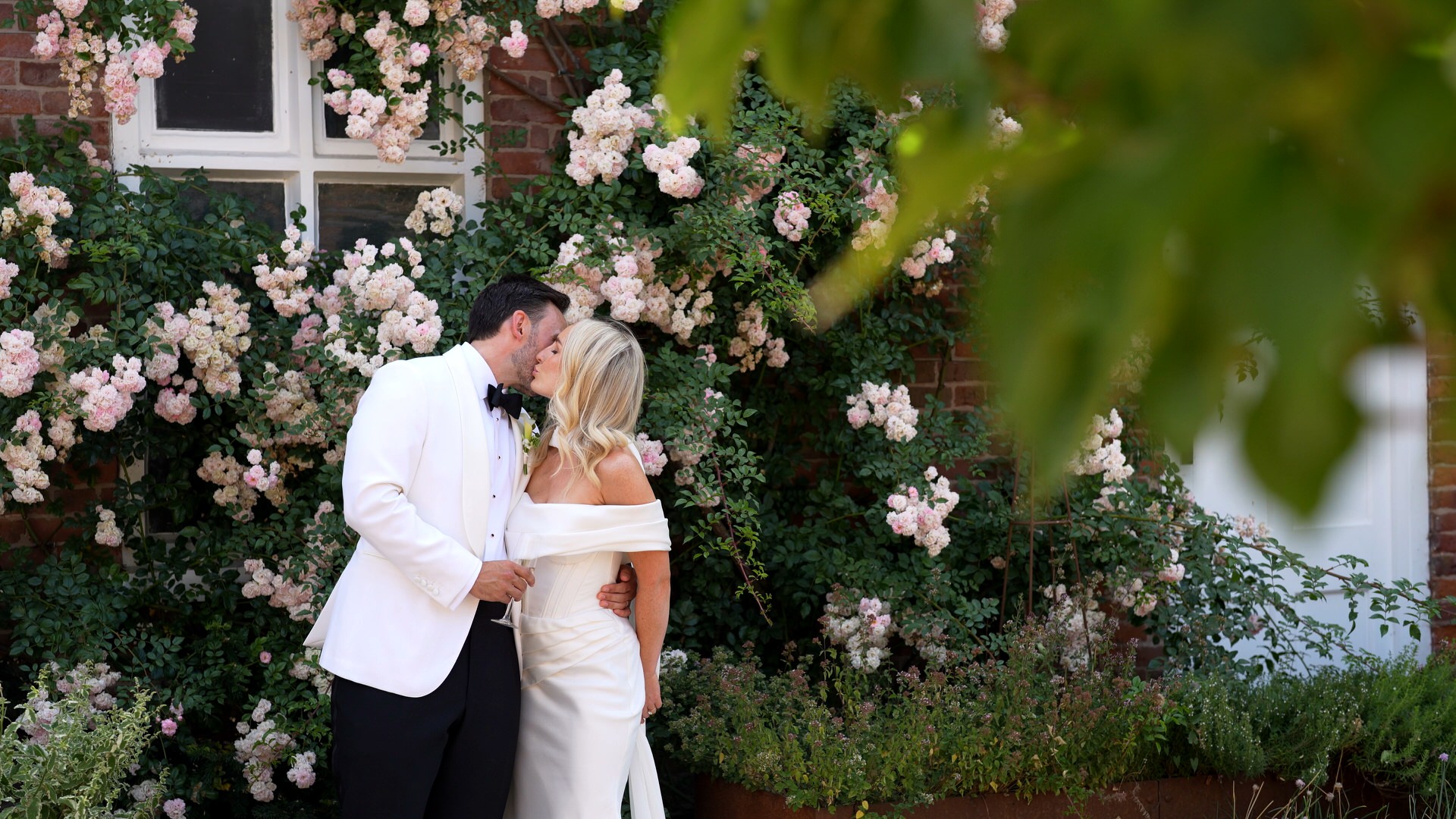a couple kiss by climbing roses outside Iscoyd Park