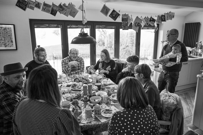 a wide shot of a large family gathering at home together for a photoshoot in Lancashire