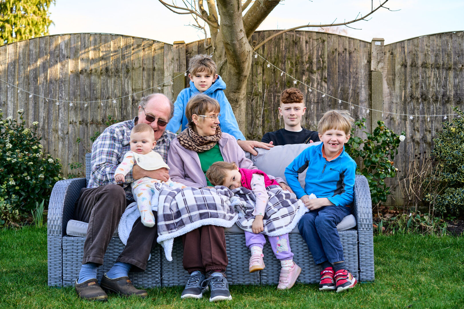 grandparents sit with their grandchildren in their garden in Rufford